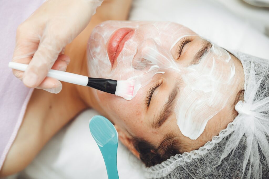 A cosmetologist does facial care and apply a face mask.