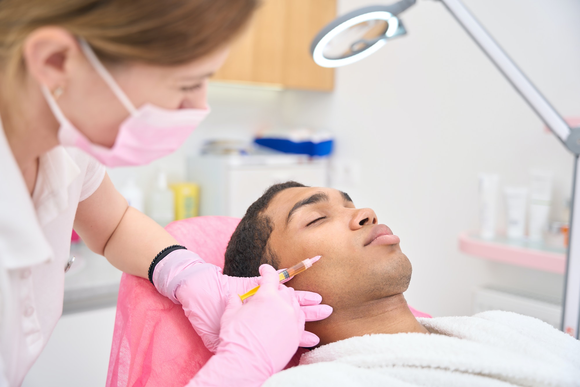 Beauty salon customer receiving cheek filler injection